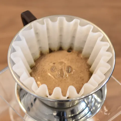 A pour-over cone brewing into a glass carafe.