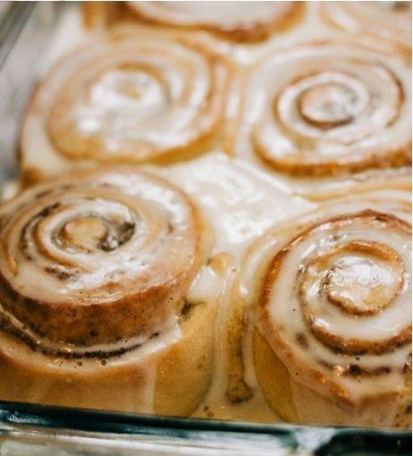 Iced cinnamon rolls in a glass pan.